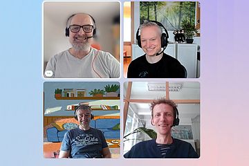 A screenshot of a video call with four smiling men, each in a separate frame. They are wearing headsets and sitting in different indoor settings with various backgrounds.