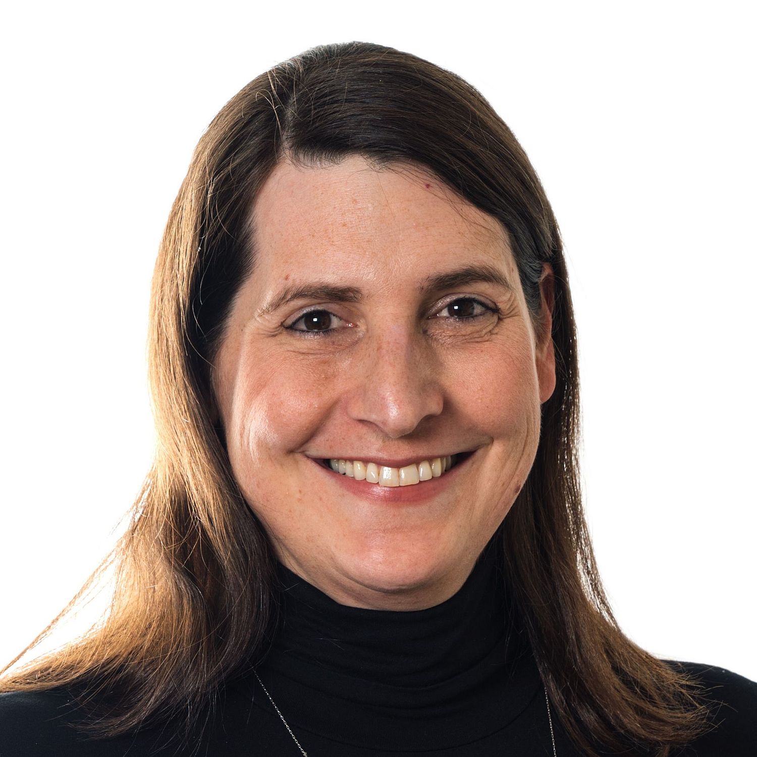 A woman with straight, shoulder-length hair is smiling at the camera. She is wearing a black turtleneck and a simple necklace with a small pendant. The background is plain white.