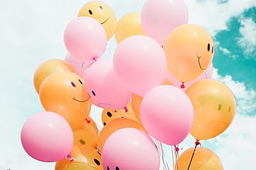 Orange balloons with smiling faces and pink balloons with sad faces.
