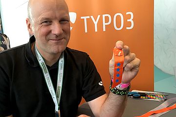 Man holding TYPO3 pin with ribbon with four stars