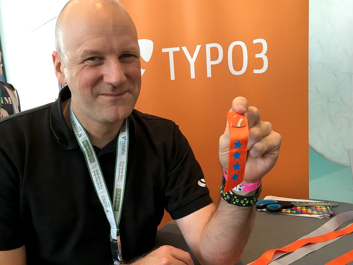 Man holding TYPO3 pin with ribbon with four stars