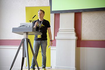 Man in black t-shirt and jeans behind a lectern