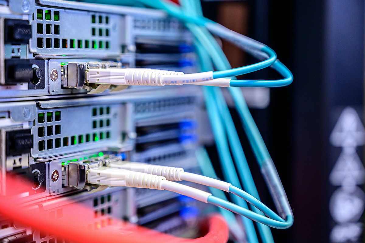 Close-up of computer servers with various colored cables connected to the ports. The focus is on the blue and white cables plugged into the front panel, indicating data or network connections.