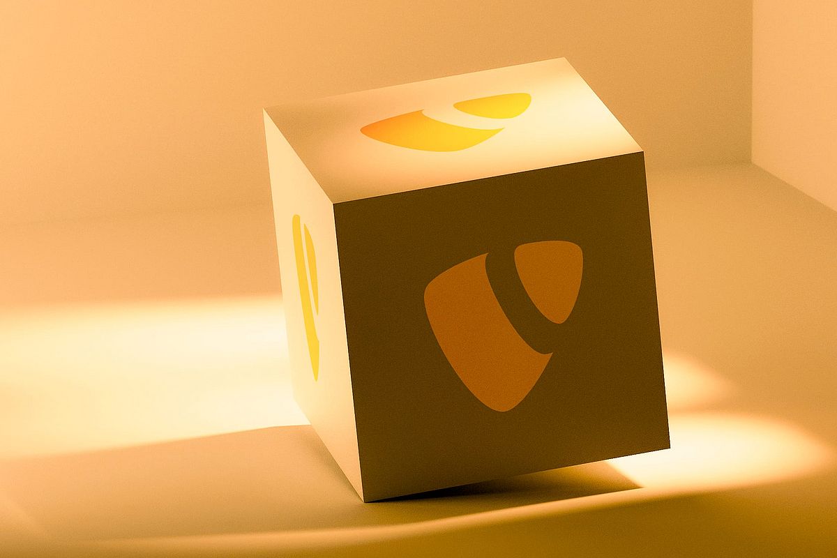 A white cube with an orange TYPO3 logo on its sides sits on a smooth surface, bathed in warm, golden light with soft shadows.
