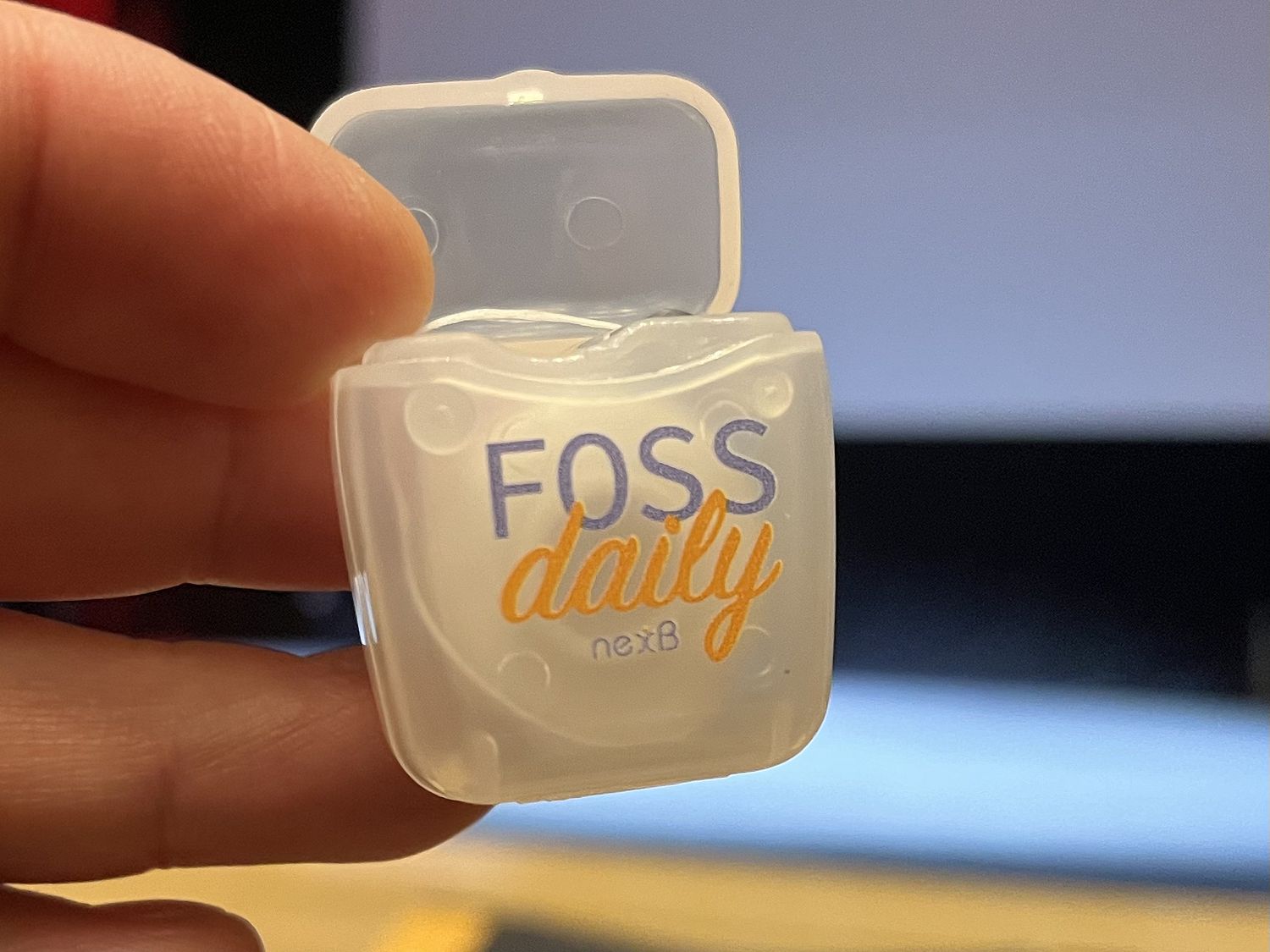 Small dental floss container with the text "FOSS daily".