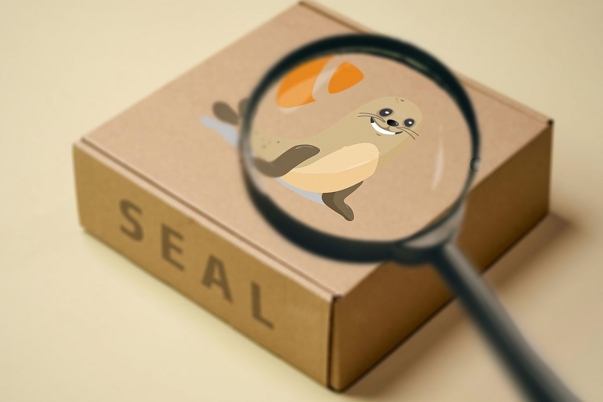 A magnifying glass hovers over a cardboard box labeled SEAL, focusing on a cartoon seal illustration printed on the box.