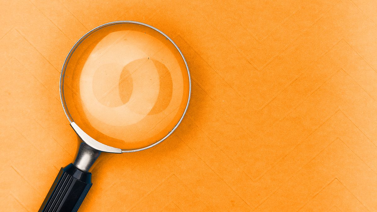Magnifying glass on orange background.