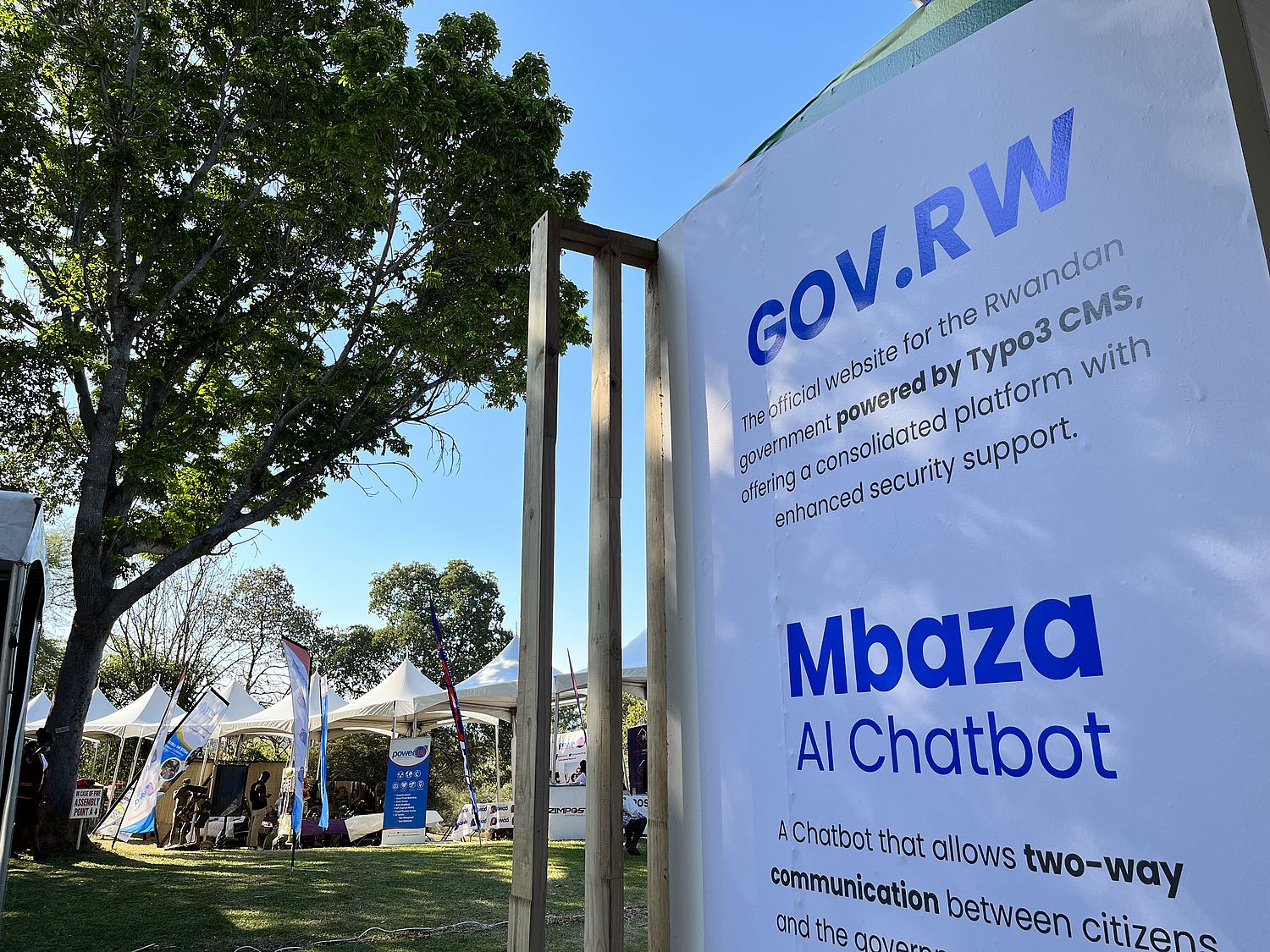 White vertical banner with "gov.rw" in an outdoor setting with trees.