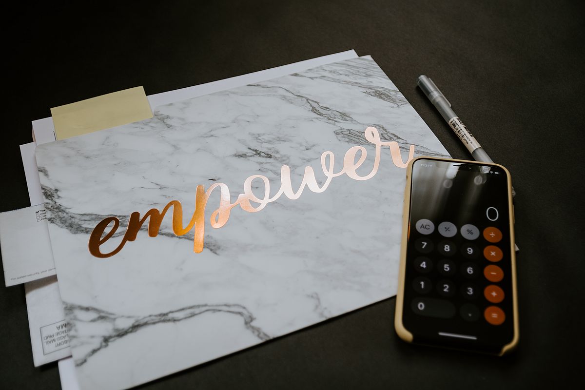 Sheet of paper with the word "empower" in golden writing next to a calculator.