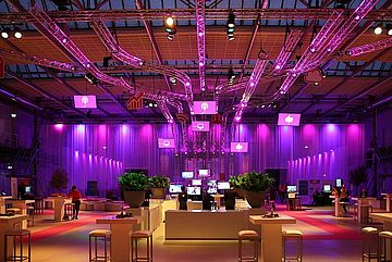 Convention center lounge with stools and tables. Magento light and computer screens in background.