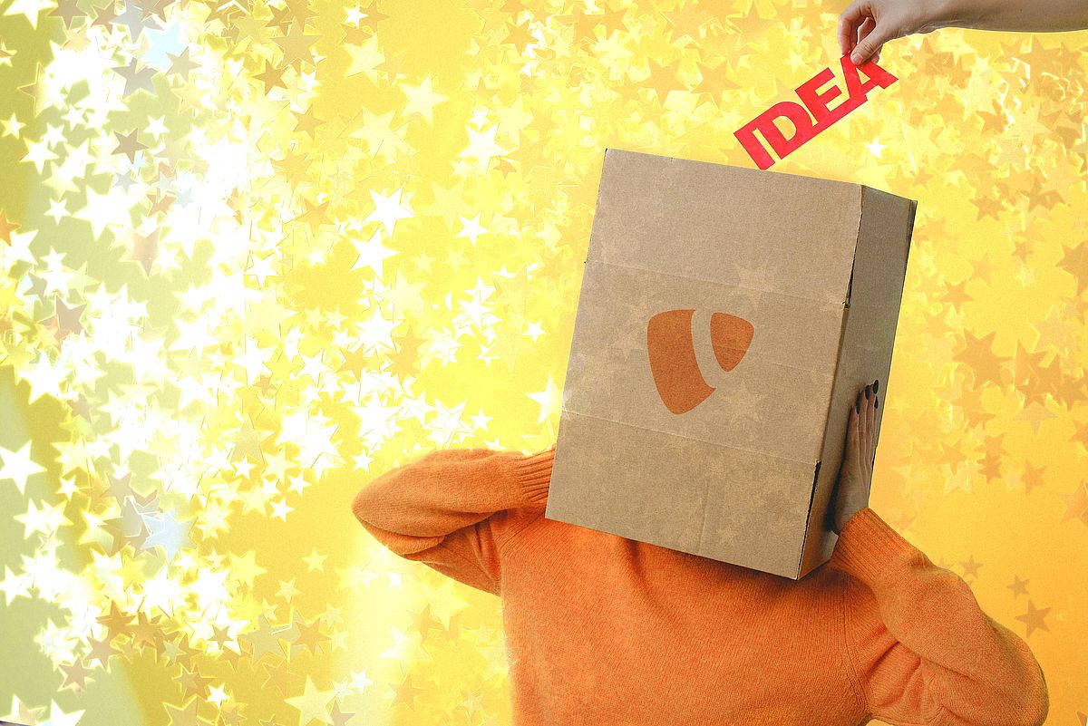 A person in an orange sweater with a cardboard box with the TYPO3 logo over their head stands against a yellow, star-filled background. A hand places the word IDEA into the box.