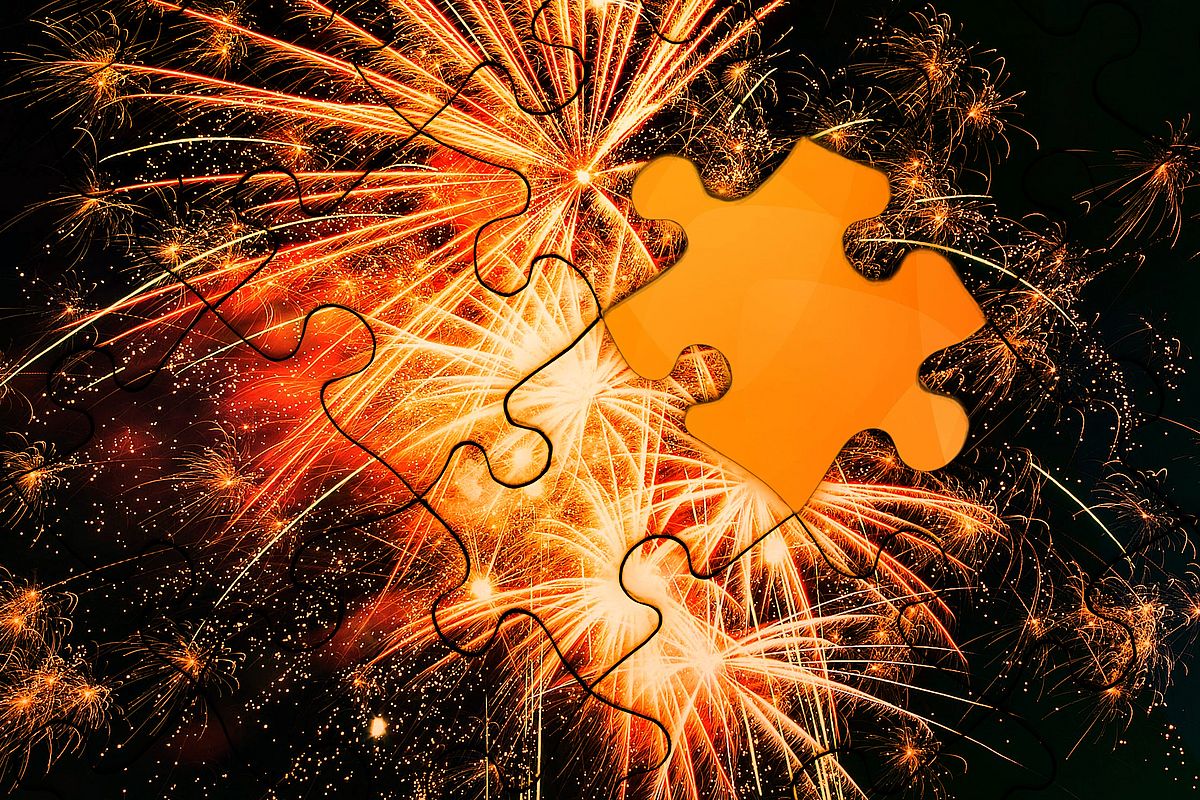 A vibrant fireworks display with glowing orange and yellow sparks fills the night sky. Overlaid on the image is a large orange highlighted puzzle piece.