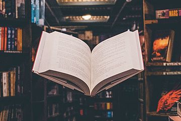 Open book hovering inside a circle of stacked books.