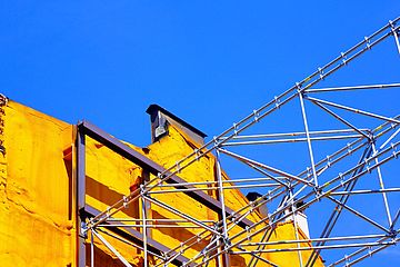 Gray metal construction frame next to a yellow brick wall.