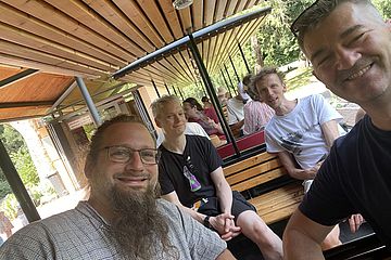 Men sitting in a small open train carriage.