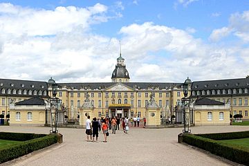 Entrance to the courtyard of a palace in yellow stone; baroque-looking architecture.