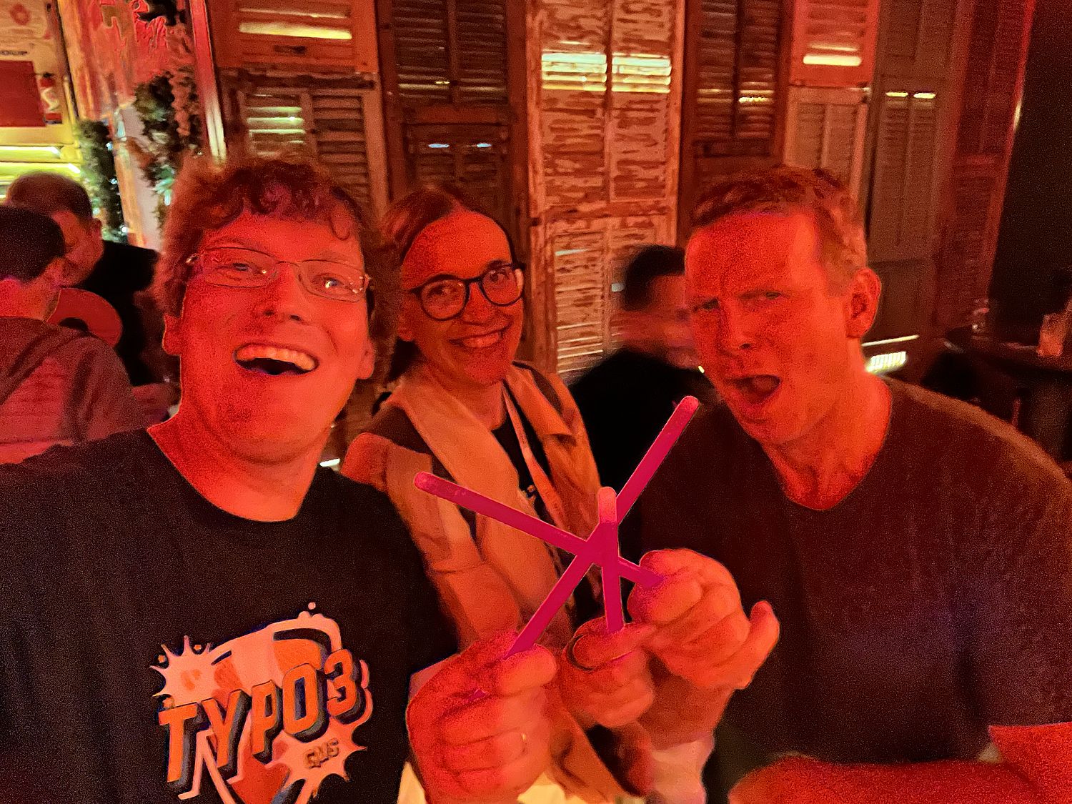 A woman and two men holding party sticks together as if they were swords.