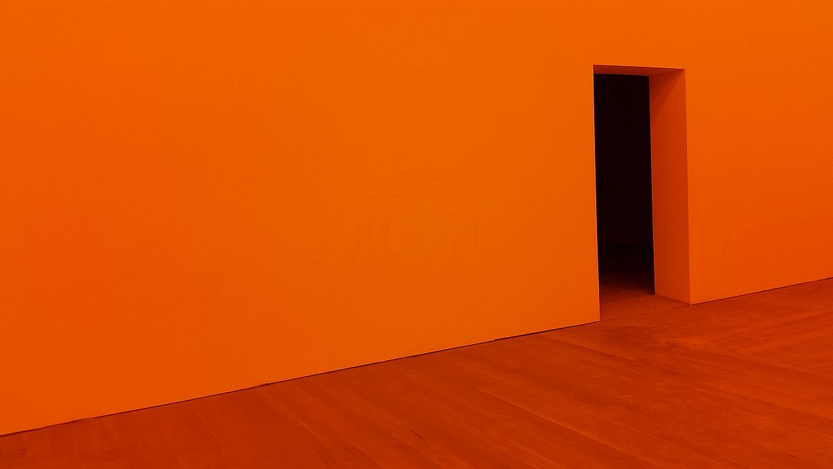 Orange floor and wall. Black door opening.