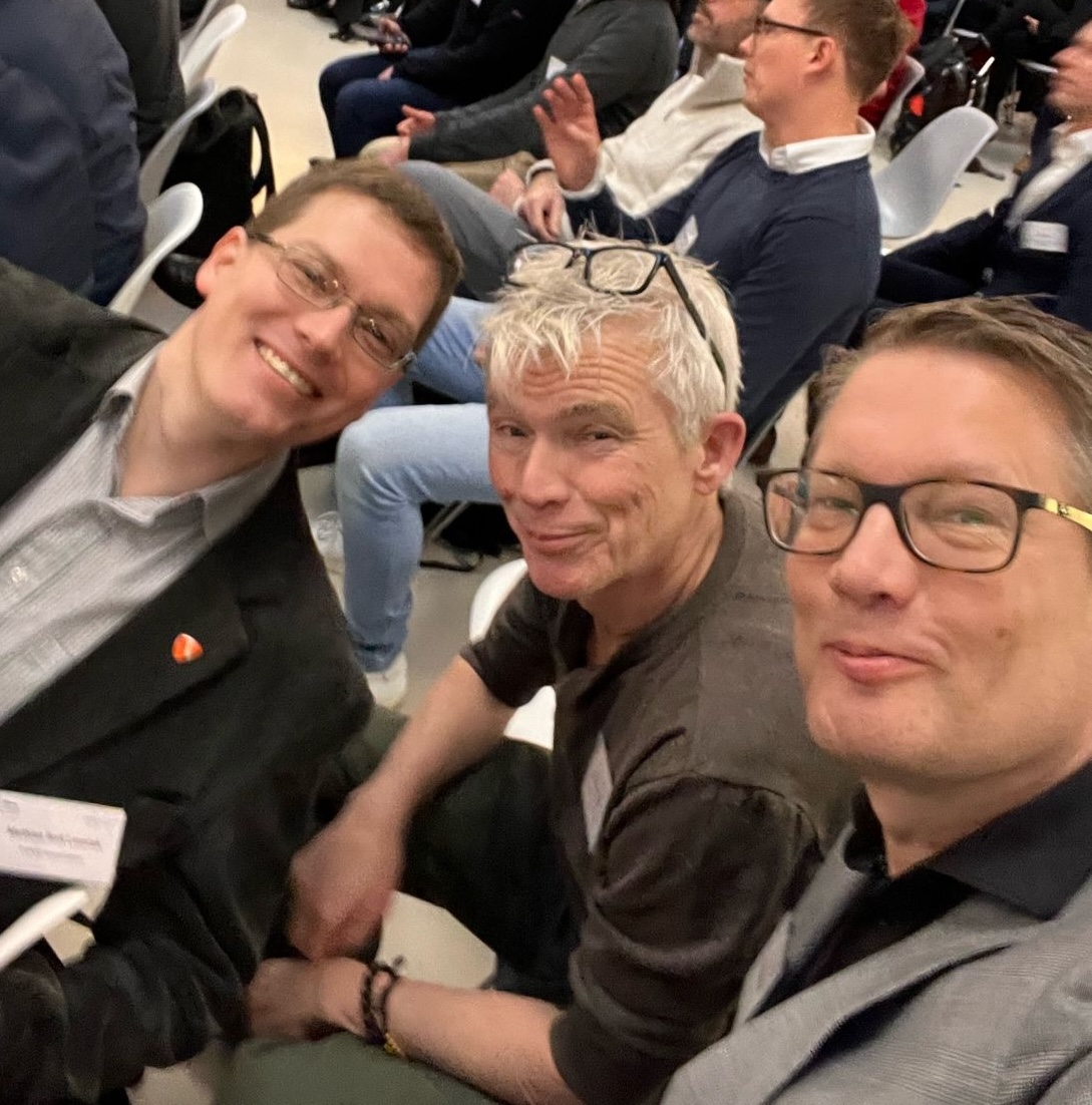 Selfie of three men at a conference.