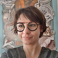 Woman with round glasses and dark hair.